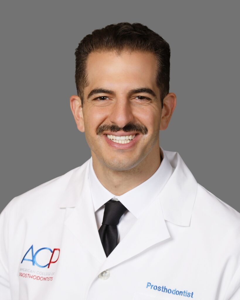 Dr. Justin W. Nichols, DDS, MS, prosthodontist, in a white coat with American College of Prosthodontists insignia